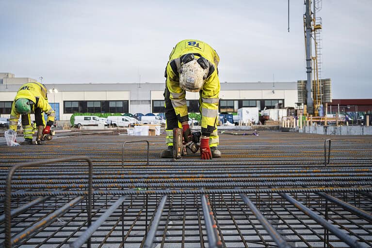 Reinforced concrete construction site workers working with rebar for building foundation.