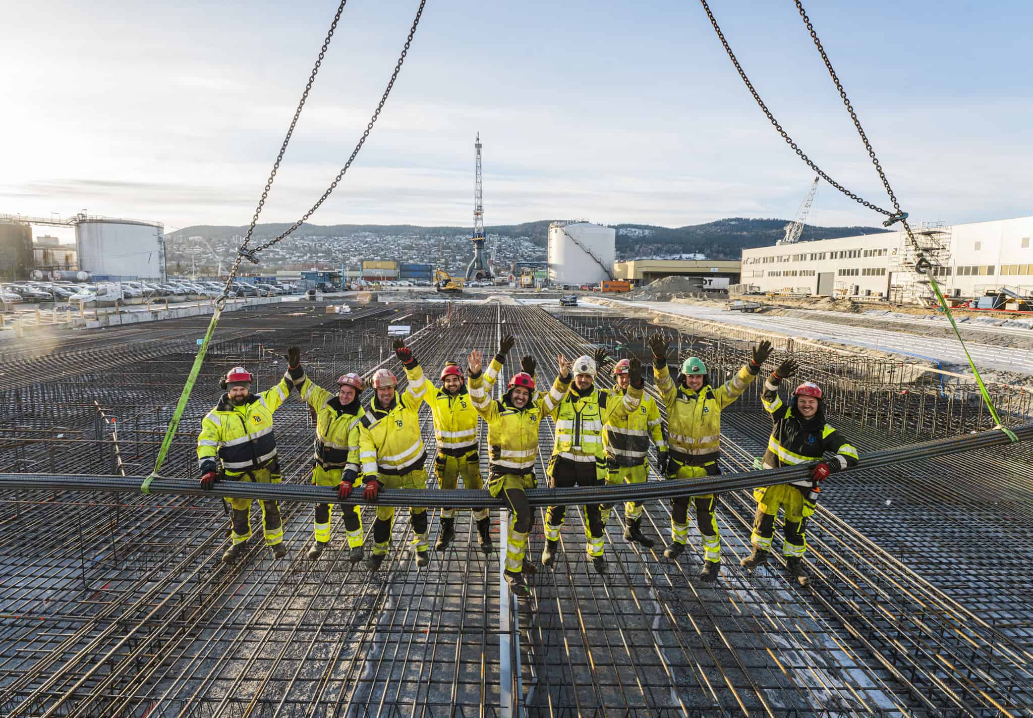 High-angle view of construction workers in safety gear standing on reinforced concrete foundation at a building site, showcasing construction and concrete pouring services.