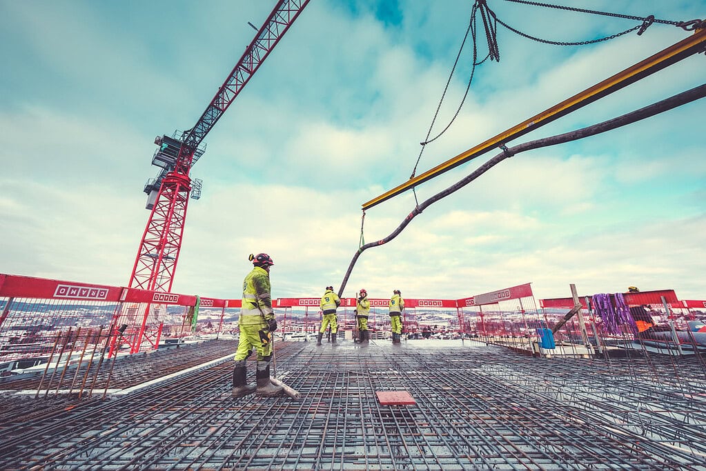 Reinforced concrete construction site with workers and crane at a high-rise building project.