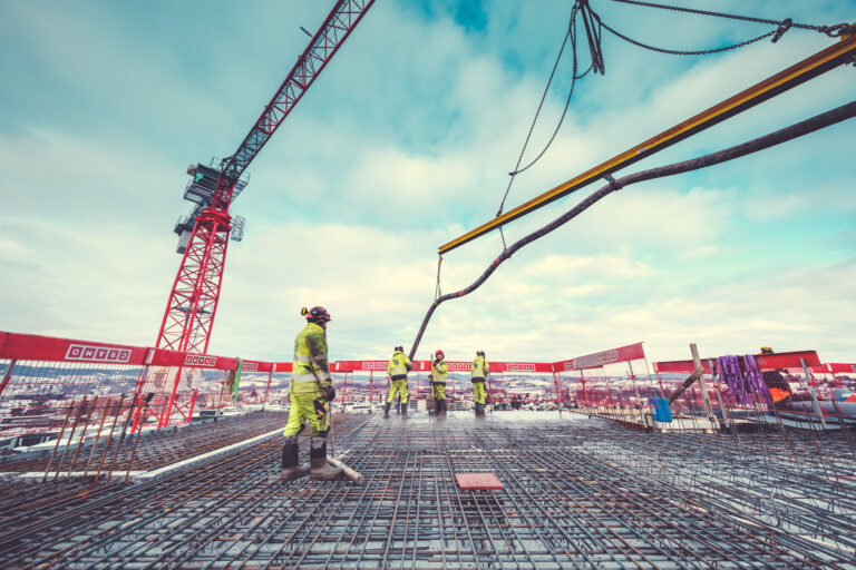 Reinforced concrete construction site with workers and crane at a high-rise building project.