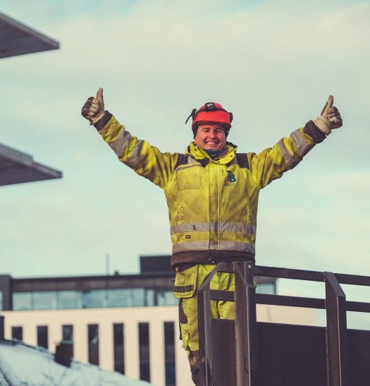 High-visibility worker in safety gear celebrating on construction site, representing quality concrete and construction services by Trio Betong.
