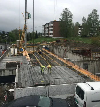 Reinforced concrete foundation construction at a building site, with workers and heavy machinery on-site.